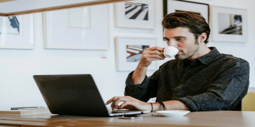 imagem de homem tomando café ao trabalhar em notebook