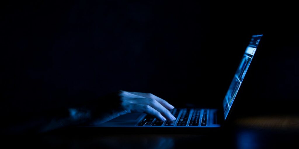 imagem de pessoa anônima usando notebook no escuro